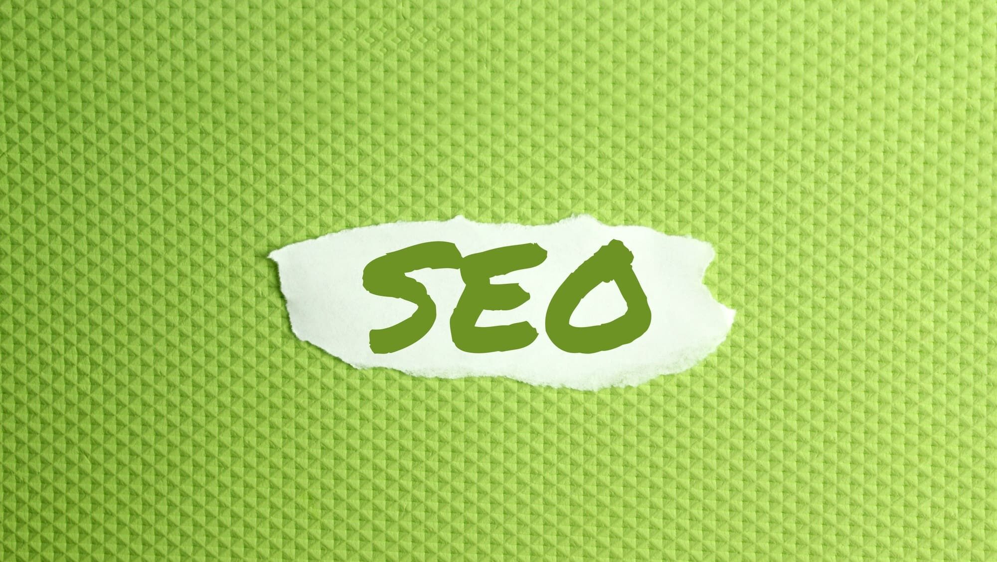 a torn paper written with inscription SEO on a green background